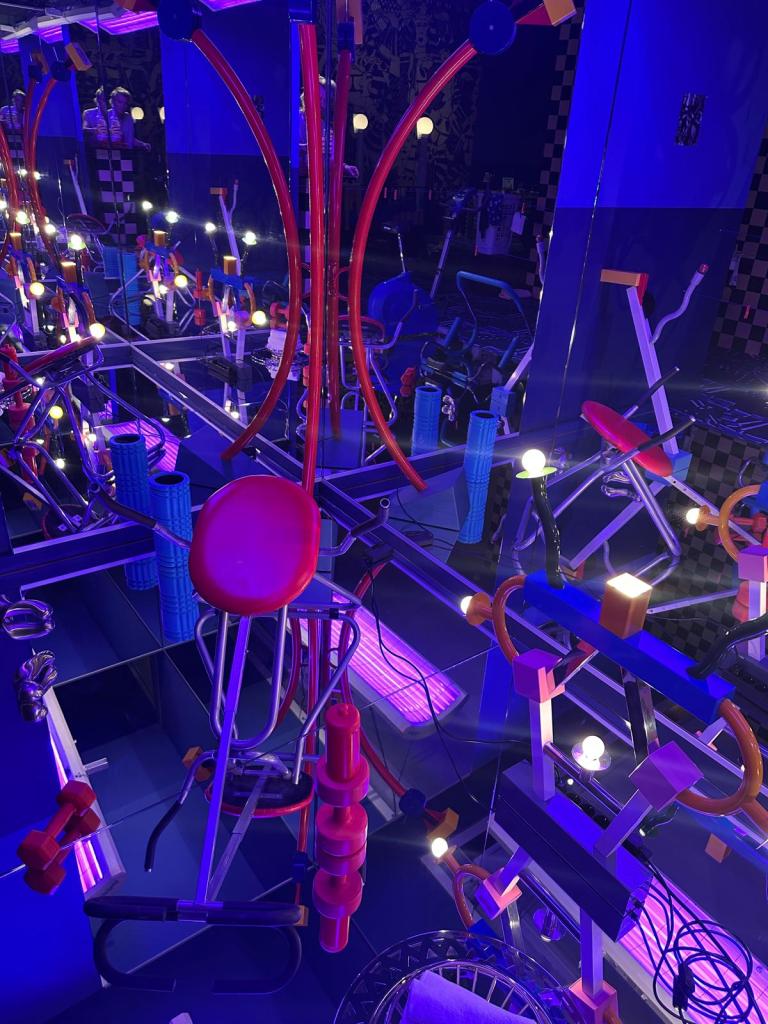 Welcome to the dreamhouse Dwaal door een levensgroot droomhuis in het Groninger Museum. Alle ruimtes – van de woonkamer en de slaapkamer tot de tuin – staan in deze tentoonstelling vol met postmodern design uit de eigen collectie van het museum. Een haast filmische wereld komt tot leven waarin details, contrasten, kleuren en humor centraal staan. Van rondslingerend speelgoed tot gebruikte asbakken – de kamers ademen het dagelijks leven en spelen met de imperfectie die echte interieurs kenmerkt. Het Groninger Museum beschikt over de grootste museale collectie postmodern design in het land, opgebouwd sinds de jaren tachtig onder leiding van voormalig directeur Frans Haks. In Welcome to the Dreamhouse! is werk te zien van invloedrijke ontwerpers als Alessandro Mendini, Ettore Sottsass en andere leden van de Memphis-groep, waaronder Michele de Lucchi, Masanori Umeda, George Sowden en Nathalie du Pasquier. Ook is er aandacht voor Philippe Starck, ontwerper van een van de paviljoens van het museum, en voor ontwerpers als Studio Job, Maarten Baas en Jaime Hayon, die elk op hun eigen manier het postmodernisme een nieuwe invulling geven. De tentoonstelling is vormgegeven door Marloes en Wikke, gerenommeerde scenografen voor theater en opera, die met hun onconventionele stijl zorgen voor een speelse en theatrale presentatie. Het Groninger Museum 2025 Ontwerp en Samenstelling Marloes en Wikke Conservator Ruud Schenk Lichtontwerp Yuri Schreuders Geluidsontwerp Daan Hofman Styling assistent Juliette Mout Grafische vormgeving Rudo Menge Hoofd collectie Marieke van Loenhout Stage M\\W Menno Meijners Peter Duel