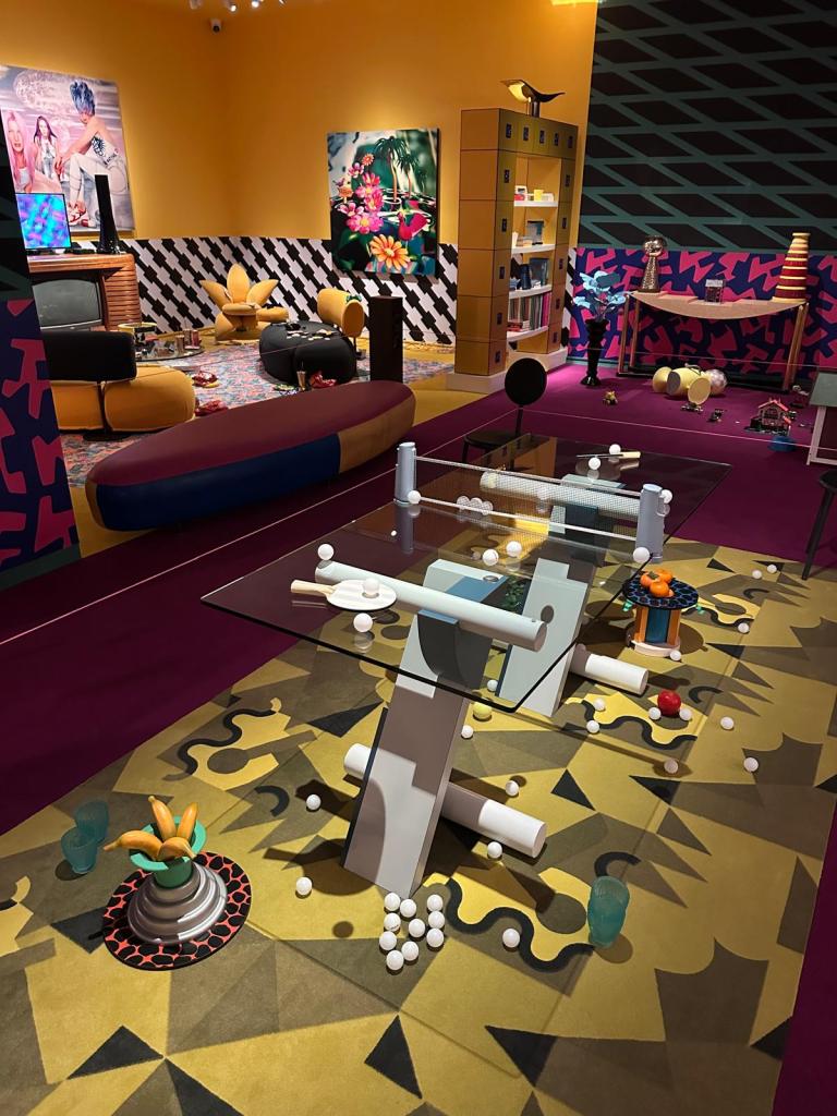 Welcome to the dreamhouse Dwaal door een levensgroot droomhuis in het Groninger Museum. Alle ruimtes – van de woonkamer en de slaapkamer tot de tuin – staan in deze tentoonstelling vol met postmodern design uit de eigen collectie van het museum. Een haast filmische wereld komt tot leven waarin details, contrasten, kleuren en humor centraal staan. Van rondslingerend speelgoed tot gebruikte asbakken – de kamers ademen het dagelijks leven en spelen met de imperfectie die echte interieurs kenmerkt. Het Groninger Museum beschikt over de grootste museale collectie postmodern design in het land, opgebouwd sinds de jaren tachtig onder leiding van voormalig directeur Frans Haks. In Welcome to the Dreamhouse! is werk te zien van invloedrijke ontwerpers als Alessandro Mendini, Ettore Sottsass en andere leden van de Memphis-groep, waaronder Michele de Lucchi, Masanori Umeda, George Sowden en Nathalie du Pasquier. Ook is er aandacht voor Philippe Starck, ontwerper van een van de paviljoens van het museum, en voor ontwerpers als Studio Job, Maarten Baas en Jaime Hayon, die elk op hun eigen manier het postmodernisme een nieuwe invulling geven. De tentoonstelling is vormgegeven door Marloes en Wikke, gerenommeerde scenografen voor theater en opera, die met hun onconventionele stijl zorgen voor een speelse en theatrale presentatie. Het Groninger Museum 2025 Ontwerp en Samenstelling Marloes en Wikke Conservator Ruud Schenk Lichtontwerp Yuri Schreuders Geluidsontwerp Daan Hofman Styling assistent Juliette Mout Grafische vormgeving Rudo Menge Hoofd collectie Marieke van Loenhout Stage M\\W Menno Meijners Peter Duel