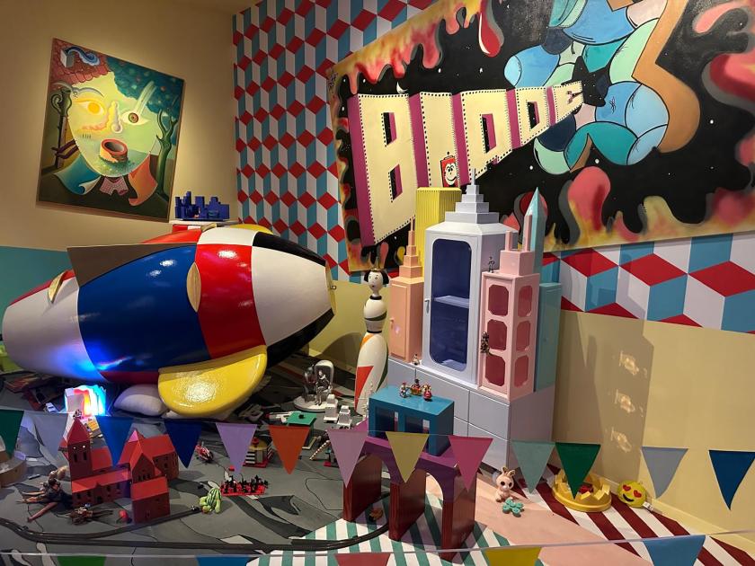 Welcome to the dreamhouse Dwaal door een levensgroot droomhuis in het Groninger Museum. Alle ruimtes – van de woonkamer en de slaapkamer tot de tuin – staan in deze tentoonstelling vol met postmodern design uit de eigen collectie van het museum. Een haast filmische wereld komt tot leven waarin details, contrasten, kleuren en humor centraal staan. Van rondslingerend speelgoed tot gebruikte asbakken – de kamers ademen het dagelijks leven en spelen met de imperfectie die echte interieurs kenmerkt. Het Groninger Museum beschikt over de grootste museale collectie postmodern design in het land, opgebouwd sinds de jaren tachtig onder leiding van voormalig directeur Frans Haks. In Welcome to the Dreamhouse! is werk te zien van invloedrijke ontwerpers als Alessandro Mendini, Ettore Sottsass en andere leden van de Memphis-groep, waaronder Michele de Lucchi, Masanori Umeda, George Sowden en Nathalie du Pasquier. Ook is er aandacht voor Philippe Starck, ontwerper van een van de paviljoens van het museum, en voor ontwerpers als Studio Job, Maarten Baas en Jaime Hayon, die elk op hun eigen manier het postmodernisme een nieuwe invulling geven. De tentoonstelling is vormgegeven door Marloes en Wikke, gerenommeerde scenografen voor theater en opera, die met hun onconventionele stijl zorgen voor een speelse en theatrale presentatie. Het Groninger Museum 2025 Ontwerp en Samenstelling Marloes en Wikke Conservator Ruud Schenk Lichtontwerp Yuri Schreuders Geluidsontwerp Daan Hofman Styling assistent Juliette Mout Grafische vormgeving Rudo Menge Hoofd collectie Marieke van Loenhout Stage M\\W Menno Meijners Peter Duel